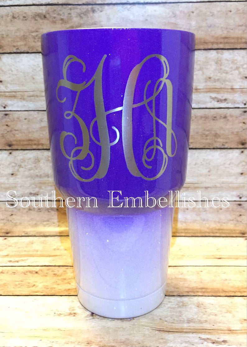 May include: A purple and white ombre glitter tumbler with a silver monogram "HA" on the purple portion. The tumbler is made by Southern Embellishes.