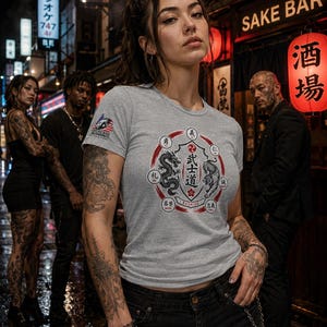 May include: A heather gray short-sleeve t-shirt featuring a circular graphic on the chest with a dragon, a tiger, and Japanese kanji characters surrounding the central text Bushido. A small American flag logo is printed on the right sleeve.