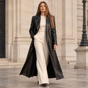 Peut inclure: Un long manteau en cuir noir porté sur un haut côtelé crème et un pantalon large taille haute de couleur crème. Le manteau présente un col à revers et des manches longues, tandis que le pantalon a une coupe droite et structurée.