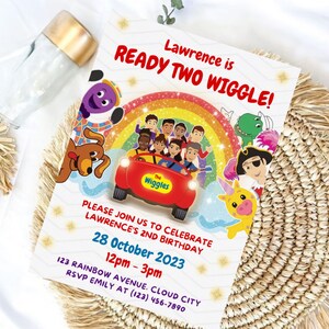 May include: A rectangular birthday invitation card featuring The Wiggles characters in a red car under a rainbow. Text reads: Lawrence is READY TWO WIGGLE! PLEASE JOIN US TO CELEBRATE LAWRENCE'S 2ND BIRTHDAY 28 October 2023 12pm - 3pm 123 RAINBOW AVENUE. CLOUD CITY RSVP EMILY AT (123) 456-7890.