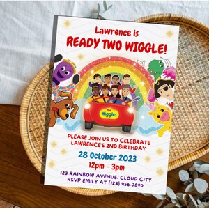 May include: A rectangular birthday invitation card featuring The Wiggles characters in a red car under a rainbow. Text reads: Lawrence is READY TWO WIGGLE! PLEASE JOIN US TO CELEBRATE LAWRENCE'S 2ND BIRTHDAY 28 October 2023 12pm - 3pm 123 RAINBOW AVENUE. CLOUD CITY RSVP EMILY AT (123) 456-7890.