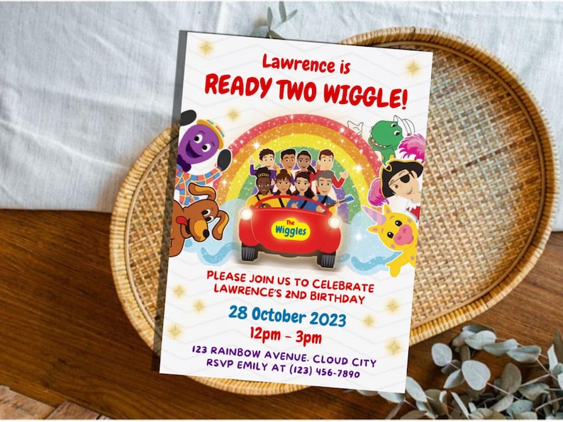 May include: A rectangular birthday invitation card featuring The Wiggles characters in a red car under a rainbow. Text reads: Lawrence is READY TWO WIGGLE! PLEASE JOIN US TO CELEBRATE LAWRENCE'S 2ND BIRTHDAY 28 October 2023 12pm - 3pm 123 RAINBOW AVENUE. CLOUD CITY RSVP EMILY AT (123) 456-7890.