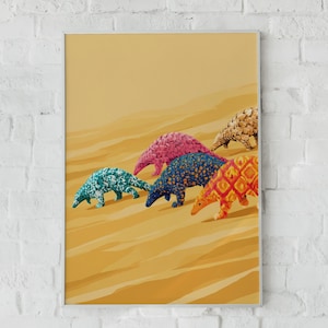 May include: A framed art print featuring four stylized pangolins walking across a golden sand dune landscape. The pangolins are decorated with distinct patterns in teal, pink, dark blue, and orange, while a fifth pangolin is partially visible.