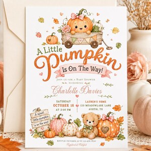 Puede incluir: Una tarjeta de invitación para baby shower con una ilustración en acuarela de una calabaza en un carro de madera, un osito de peluche y hojas de otoño. El texto dice A Little Pumpkin Is On The Way! para Charlotte Davies.