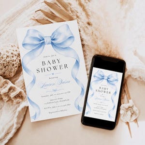 May include: A white baby shower invitation card and a smartphone displaying the same digital invitation, both featuring a large watercolor light blue bow at the top and black text that reads Baby Shower, Lauren Quinn, and event details.