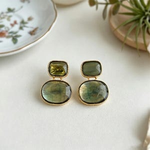 Artisan green stone drop earrings with Gold-Tone edges, arranged neatly on a neutral surface with decorative plate background.