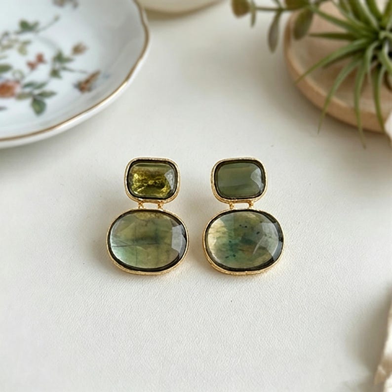 Artisan green stone drop earrings with Gold-Tone edges, arranged neatly on a neutral surface with decorative plate background.