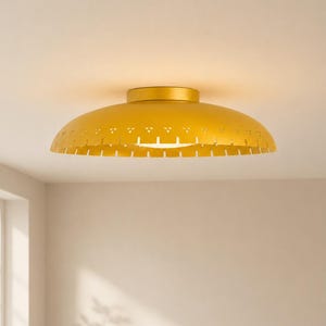 Puede incluir: Una lámpara de techo circular de montaje empotrado con acabado en oro mate. La pantalla ancha y poco profunda en forma de cúpula presenta un borde decorativo con pequeños recortes triangulares y ranuras verticales en la parte inferior.