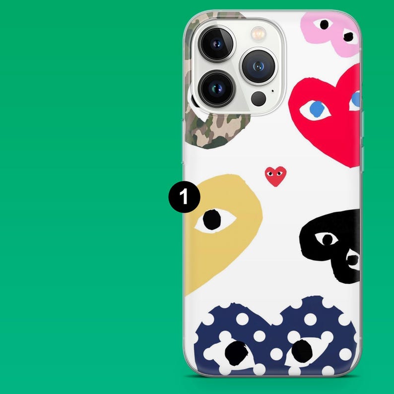 Op de afbeelding: Een doorzichtige telefoonhoes met een witte achtergrond met kleurrijke, cartoonachtige hart- en oogontwerpen. De harten zijn rood, roze en blauw met witte stippen. De ogen zijn geel, zwart en camouflage.