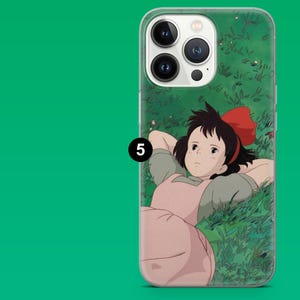 May include: Clear phone case featuring a cartoon illustration of a girl with a red bow in her hair, lying in a field of green grass. The case has a green background with a white border and a black number 5.