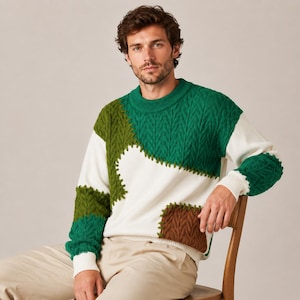 Puede incluir: Un suéter de manga larga con cuello redondo que presenta un diseño de bloques de color con secciones en blanco, verde bosque, verde oliva y marrón. La prenda incorpora un patrón de punto trenzado en los paneles verdes y marrones y un acabado liso.