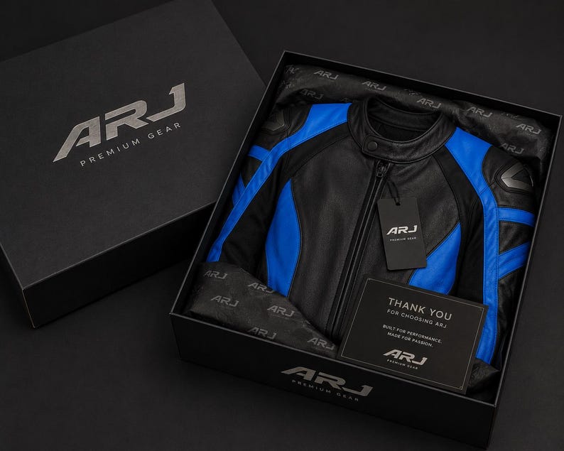 May include: A black and blue leather motorcycle jacket with a mandarin collar and front zipper, presented in a black branded gift box. The box includes branded tissue paper, a hanging tag, and a card that reads Thank You For Choosing ARJ.