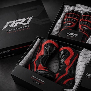 K&ouml;nnte beinhalten: Ein Paar schwarz-rote Motorradhandschuhe und ein Paar schwarz-rote Motorradstiefel in gebrandeten ARJ Motorsport-Boxen. Die Verpackung zeigt das ARJ Motorsport-Logo sowie die Texte Racing Redefined und Engineered for Speed.