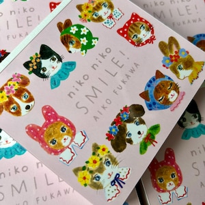 Könnte beinhalten: Eine quadratische Karte mit hellrosa Hintergrund, die Illustrationen verschiedener Tiere mit Blumenkränzen und bunten Halsbändern zeigt. Der Text "niko niko SMILE! AIKO FUKAWA" ist mittig aufgedruckt. Zu sehen sind Katzen und Hasen.