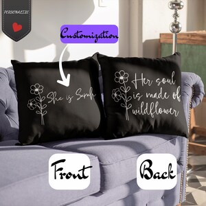 Peut inclure: Deux coussins noirs avec des motifs floraux blancs et du texte. L'un des coussins porte l'inscription "She is Sarah", l'autre "Her soul is made of wildflower". Les coussins sont sur un canapé bleu. L'image comprend les mots "Personalize", "Customization", "Front" et "Back".