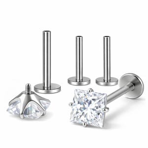 May include: A set of silver-toned labret body jewelry pieces featuring flat back posts and one square-cut clear gemstone top. The set includes three separate flat back posts and one detached square gemstone top with a threaded screw post.