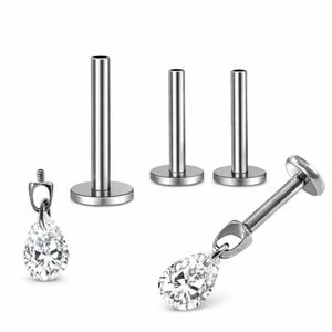 May include: A set of silver-toned metal body jewelry featuring three flat-back labret posts and two teardrop-shaped clear crystal charms. The charms have a small metal bail for attachment to the threaded posts of the labret studs.