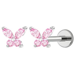 May include: A silver-toned flat back stud earring featuring a butterfly design. The butterfly is composed of two marquise-cut pink stones for the upper wings and two round-cut pink stones for the lower wings, set in a metallic frame.