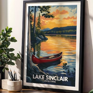 Könnte beinhalten: Ein gerahmter Kunstdruck mit einem roten Kanu, das bei Sonnenuntergang auf einem ruhigen See schwimmt. Die Illustration zeigt hohe Bäume, ein fernes Ufer und einen leuchtend orange-gelben Himmel. Unten steht der Text LAKE SINCLAIR UNITED STATES.