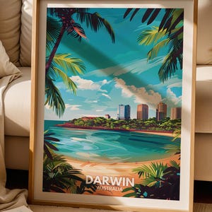 May include: A framed vertical art print featuring a vibrant illustration of the Darwin, Australia coastline. The scene depicts a sandy beach, turquoise water, and lush palm trees framing a city skyline under a bright blue sky with clouds.