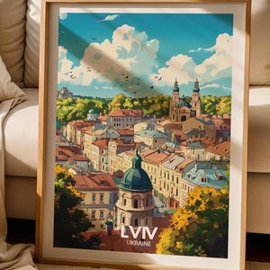 May include: A framed art print featuring a colorful illustration of the Lviv, Ukraine cityscape under a bright blue sky with white clouds. The scene depicts historic buildings with red-tiled roofs, green trees, and a prominent domed structure.