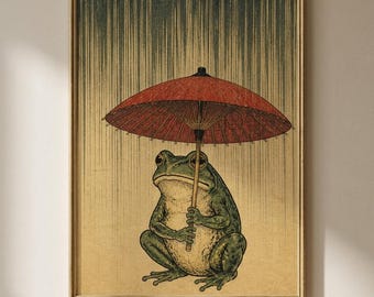 Peut inclure: Une impression d'art encadrée représentant une grenouille verte tenant un parapluie en papier rouge. Le fond présente un motif de pluie verticale passant du vert foncé en haut au beige clair en bas, le tout dans un cadre doré fin.
