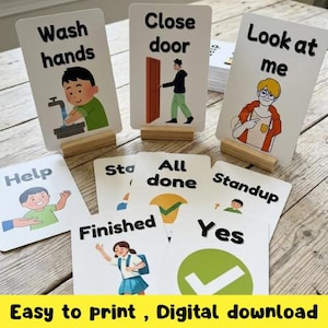 K&ouml;nnte beinhalten: Eine Sammlung wei&szlig;er Karten mit schwarzem Text und Illustrationen, darunter "Wash hands", "Close door" und "Look at me". Die Karten werden auf Holzst&auml;ndern pr&auml;sentiert. Der untere Teil des Bildes zeigt den Text "Easy to print, Digital download."