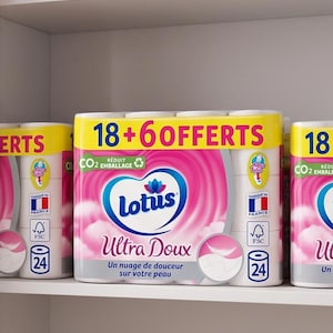 以下が含まれることがあります： 棚に積み重ねられた、Lotus Ultra Douxトイレットペーパーの複数のパッケージ。パッケージはピンクと白で、ブランド名と製品の説明がフランス語で書かれています。パッケージには「18 + 6 OFFERTS」と書かれた黄色のバナーが付いています。