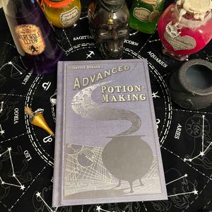 Op de afbeelding: Een verzameling benodigdheden voor het maken van drankjes, waaronder een boek getiteld "Advanced Potion-Making" en diverse drankflessen. De flessen zijn gevuld met kleurrijke vloeistoffen en versierd met etiketten en decoratieve elementen. Een zwarte ketel en een toverstaf zijn ook aanwezig.