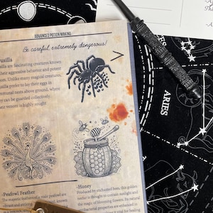 Op de afbeelding: Een gedetailleerde zwarte toverstaf ligt op een boek met illustraties van een spin, pauw en honingpot. Het boek is open op een pagina met de titel "Advanced Potion Making". Een bladwijzer luidt "After all this time? Always."