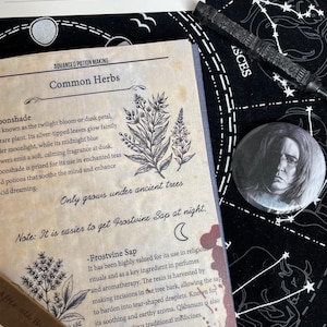 Op de afbeelding: Een verzameling fantasy-items, waaronder een pagina uit een boek getiteld "Advanced Potion Making" met botanische illustraties en tekst. Een toverstaf, een pin met een portret en een kaart met de tekst "After All This Time? Always" zijn ook zichtbaar.