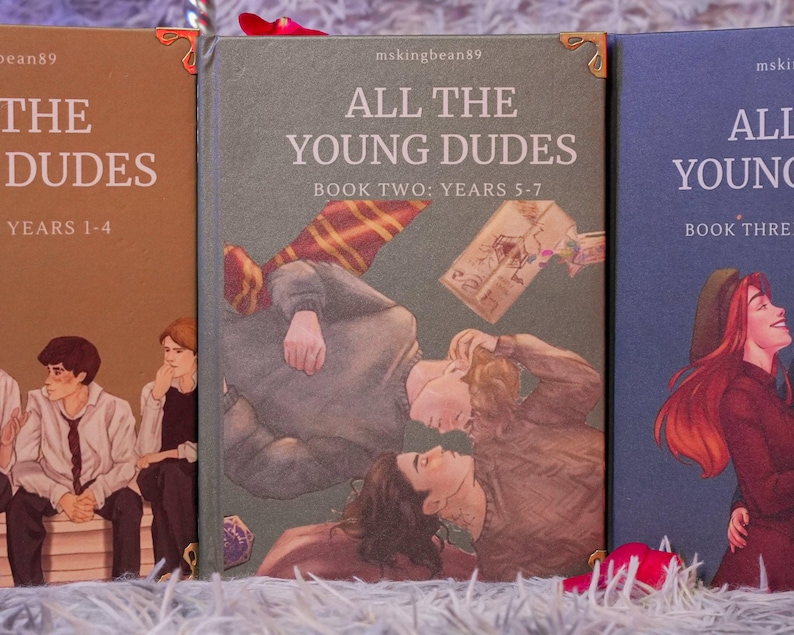 Puede incluir: Tres libros con portadas ilustradas. El primer libro es marr&oacute;n con el texto "THE DUDES YEARS 1-4". El segundo libro es verde con el texto "ALL THE YOUNG DUDES BOOK TWO: YEARS 5-7". El tercer libro es azul con el texto "ALL THE YOUNG DUDES BOOK THREE".