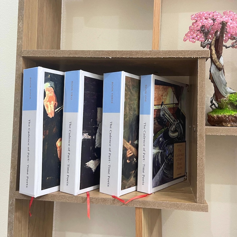 May include: Four books titled "The Cadence of Part-Time Poets" are displayed on a wooden shelf. The book spines are white with a light blue band and red ribbon bookmarks. The books have different cover art, including a hand and a record player.