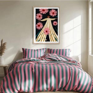 May include: A bedding set featuring a vertical striped pattern in alternating shades of pink and dark teal. Above the bed hangs a framed rectangular print depicting a figure in a long, light-colored striped dress surrounded by large pink flowers.
