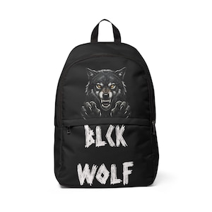 May include: A black backpack featuring a graphic of a snarling wolf with yellow eyes and sharp claws. Below the wolf, the text BLCK WOLF is printed in a distressed white font. The bag includes a top handle, a main zippered compartment, and a front pocket.