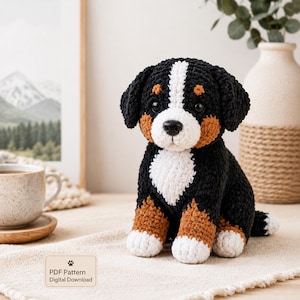 Könnte beinhalten: Gehäkelter Berner Sennenhund-Welpe in Schwarz, Weiß und Braun. Das handgefertigte Stofftier hat eine weiße Brust, Pfoten und einen Streifen im Gesicht. Das Bild enthält ein Schild mit der Aufschrift "PDF Pattern Digital Download".