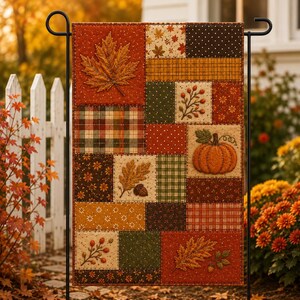 May include: A rectangular garden flag featuring a patchwork design of autumn-themed fabric squares. The pattern includes orange maple leaves, a textured pumpkin, acorns, berries, and various plaid, polka dot, and floral prints in shades of brown, orange, and green.