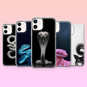 Könnte beinhalten: Fünf transparente Smartphone-Hüllen mit Schlangenmotiven. Die Designs zeigen eine weiße Schlange auf Schwarz, eine blaue Schlange, eine zentrale Kobra mit roten Augen, eine rosa Schlange und eine schwarze Schlange auf weißem Grund, alle mit Kameraaussparung.