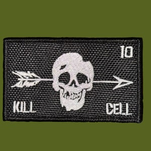 May include: A rectangular black embroidered patch featuring a white skull pierced by an arrow. The text 10 is in the top right corner, while the words KILL and CELL are embroidered in white at the bottom left and bottom right corners respectively.