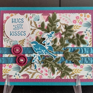 Tarjeta de cumpleaños color turquesa con un pájaro en una rama y un árbol de hojas verdes.