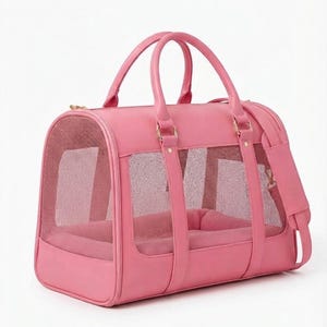 May include: A bright pink pet carrier bag featuring a structured rectangular shape with rounded edges, dual top handles, and a detachable shoulder strap. The sides and front panel include integrated mesh windows for ventilation and visibility.
