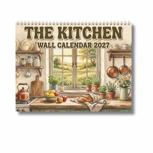 Op de afbeelding: Een wandkalender voor 2027 met de titel THE KITCHEN, voorzien van een illustratie van een rustieke keuken met uitzicht op een landschap, koperen kookgerei, kruiden in potten, een brood en vers fruit op een houten aanrecht.