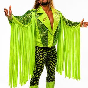 May include: A bright neon green jacket with long fringe, sequined panels, and a signature on the lapel, paired with black and neon green zebra-print leggings, matching neon green lace-up boots with fringe, a headband, and dark sunglasses.