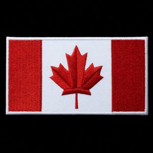 Puede incluir: Parche bordado con la bandera de Canadá. El diseño incluye un panel central blanco con una hoja de arce roja, flanqueado por dos franjas verticales rojas. El parche tiene un borde blanco y está sobre un fondo negro.
