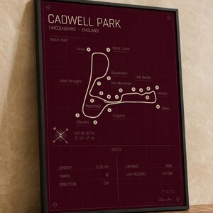 K&ouml;nnte beinhalten: Gerahmter Cadwell Park Streckenkarten-Druck. Der bordeauxfarbene Druck zeigt einen wei&szlig;en Streckenverlauf mit beschrifteten Kurven und einer Windrose. Die Karte enth&auml;lt eine Streckenl&auml;nge von 3,49 km, 18 Kurven und wurde 1938 er&ouml;ffnet.