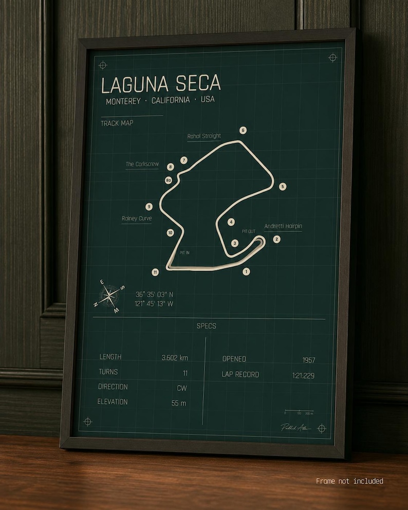 May include: Framed print of the Laguna Seca race track in Monterey, California. The track map is white on a dark green background, with the track's name and specifications. The frame is dark brown.