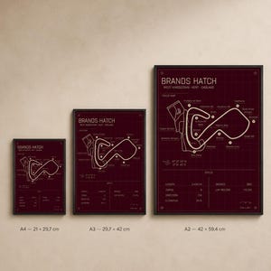 May include: Three framed prints of the Brands Hatch race track map in varying sizes. The prints feature a burgundy background with a white track layout and text. Sizes include A4 (8.3 x 11.7 inches), A3 (11.7 x 16.5 inches), and A2 (16.5 x 23.4 inches).