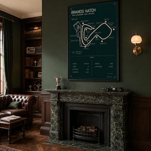 May include: A framed Brands Hatch race track map in a dark green room. The map is white on a dark green background. The room has a fireplace, a leather couch, and a bookshelf. A small model race car sits on the mantel.