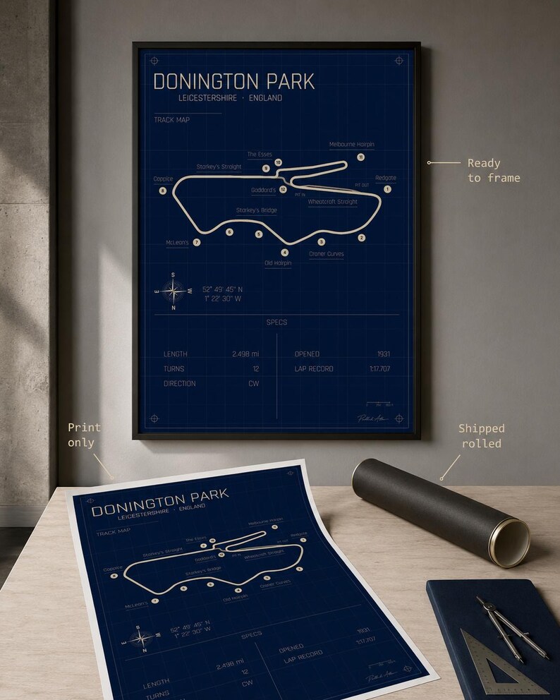 Op de afbeelding: Een ingelijste en opgerolde print van de Donington Park-circuitkaart in Leicestershire, Engeland. De kaart toont de witte circuitindeling op een donkerblauwe achtergrond, met details zoals lengte en aantal bochten.