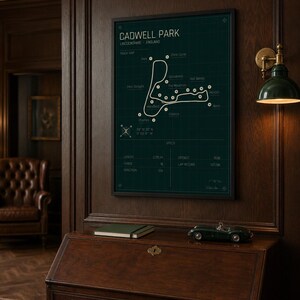 K&ouml;nnte beinhalten: Gerahmter Cadwell Park Streckenplan, Lincolnshire, England, in dunklem Gr&uuml;n und Wei&szlig;. Der Druck wird an einer dunklen Holzwand &uuml;ber einem Holzschreibtisch angezeigt. Ein gr&uuml;nes Spielzeugauto und ein gr&uuml;nes Notizbuch liegen auf dem Schreibtisch.
